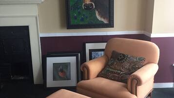 A living room with a framed painting of a cow, a fireplace, and a brown armchair with a matching ottoman.