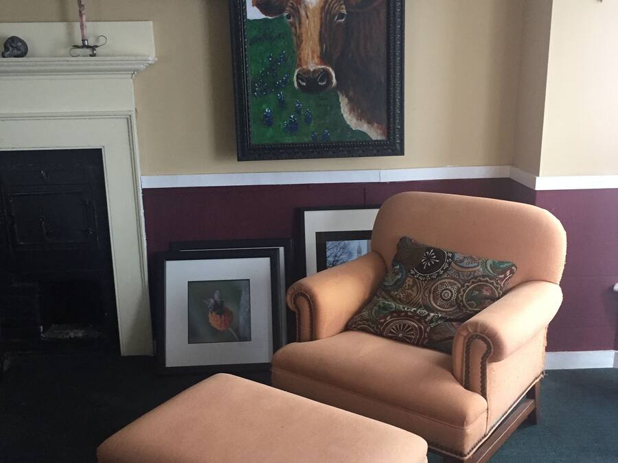 A living room with a framed painting of a cow, a fireplace, and a brown armchair with a matching ottoman.