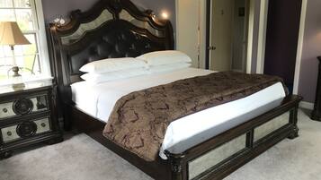 Une chambre à coucher avec un grand lit, une table de chevet, une lampe et une porte.