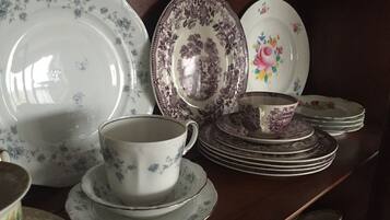 A collection of white and patterned ceramic dishes and cups on a wooden shelf.
