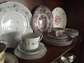 A collection of white and patterned ceramic dishes and cups on a wooden shelf.
