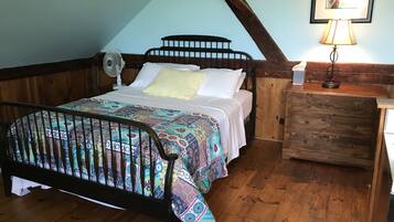 A bedroom with a wooden bed, a nightstand, a lamp, and a ceiling fan.