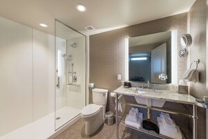 Un baño moderno con ducha de vidrio, inodoro y tocador con espejo.