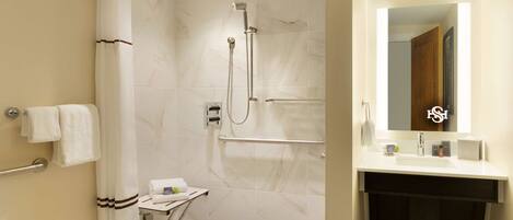 Une salle de bain moderne équipée d’une douche, d’un meuble-lavabo avec miroir et d’un porte-serviettes.