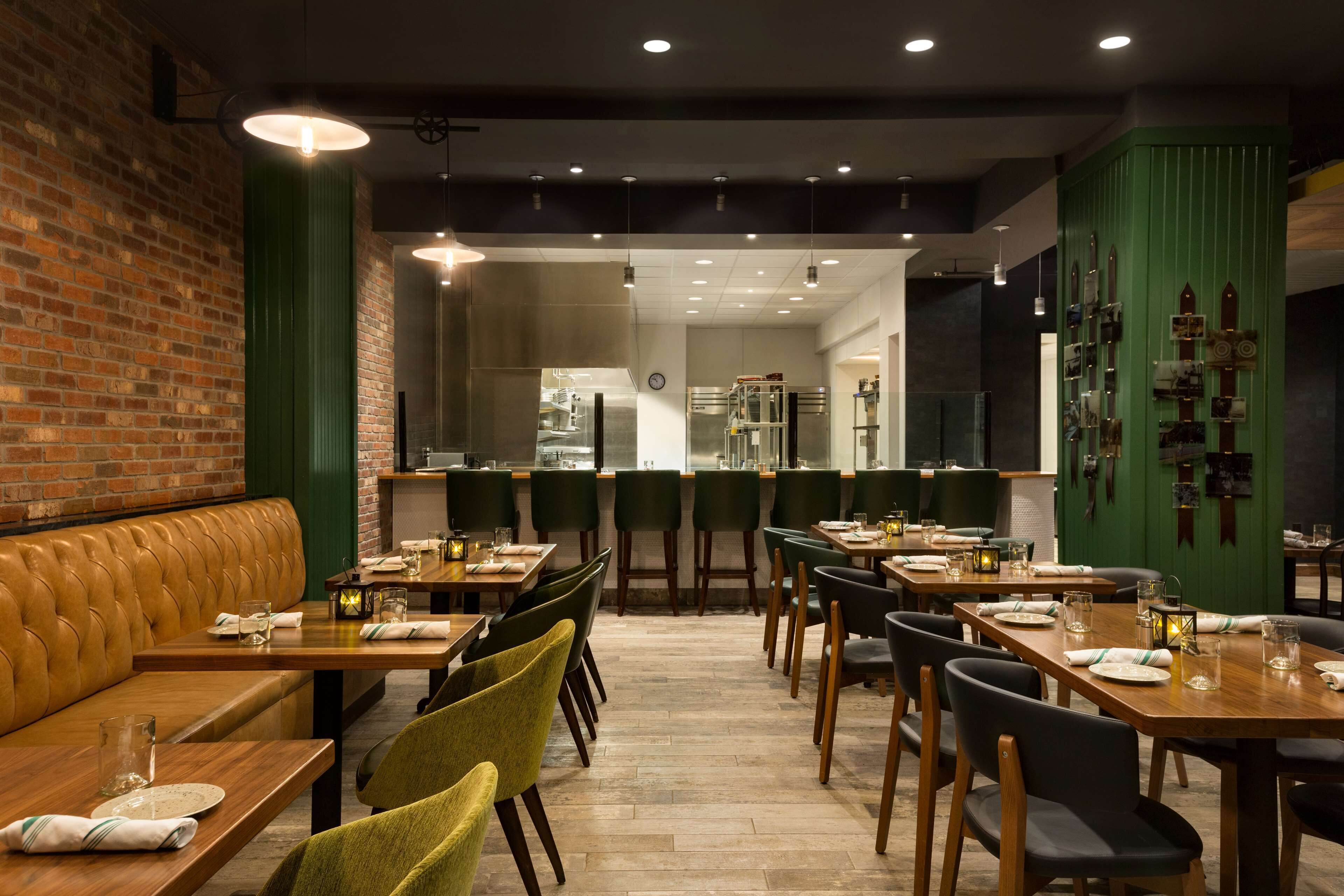 Ein Restaurant mit Holztischen und -stühlen, einer Ziegelwand und einer Wand in Grüntönen.