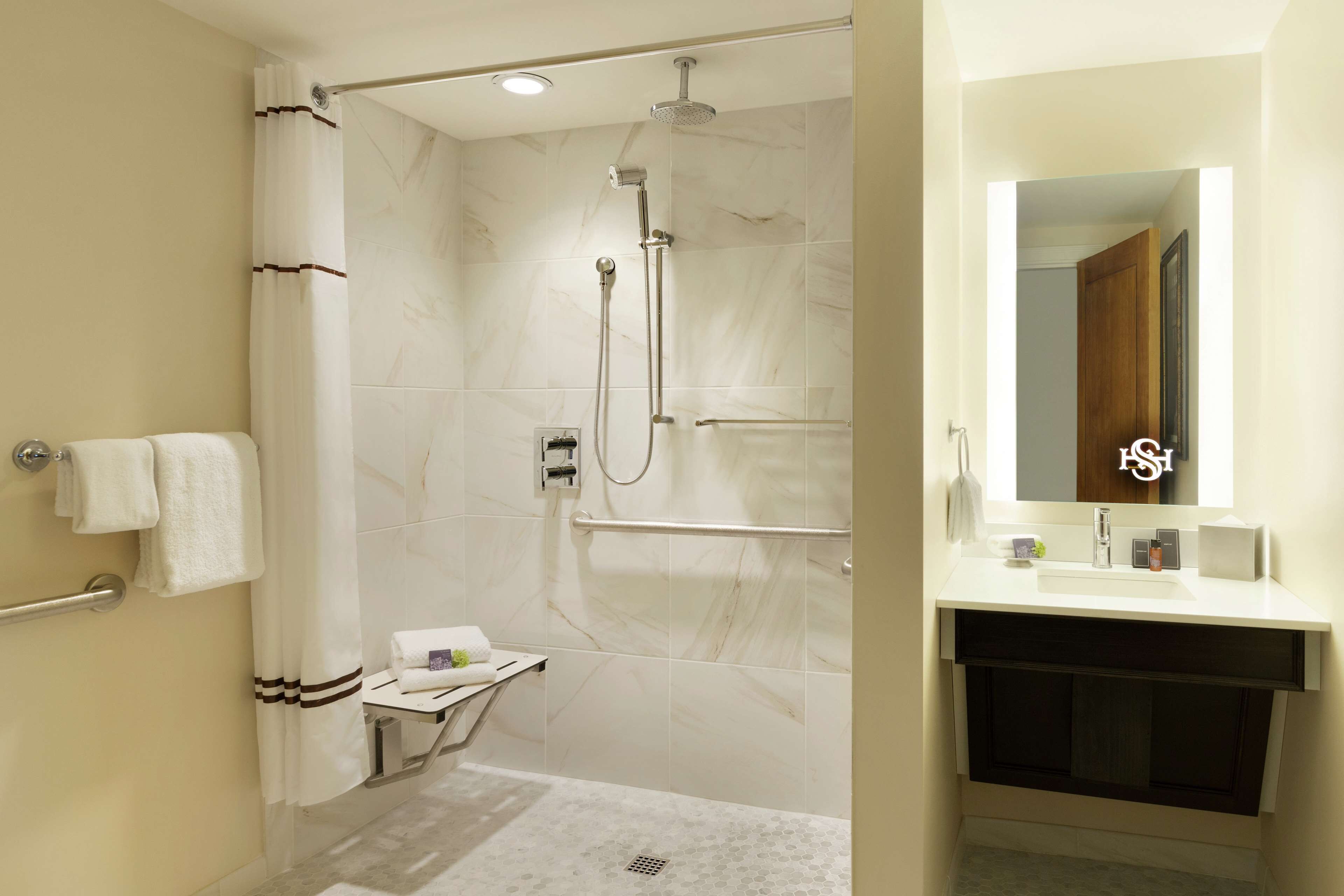 A modern bathroom with a shower, a vanity with a mirror, and a towel rack.