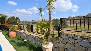 Un espacio al aire libre con jardines, un muro de piedra, una cerca metálica y vistas a un campo de golf.