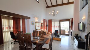 Un área de estar amplia con una mesa de comedor, sillas, un sofá y un televisor.
