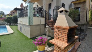 Una propiedad residencial con piscina, zona de barbacoa de ladrillo y jardín bien cuidado.