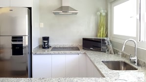 A modern kitchen with a stainless steel refrigerator, a coffee maker, a microwave, and a sink with a faucet. - 9 Bahias Condos (Santa María Huatulco)