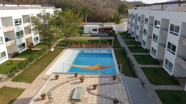 A modern hotel with a swimming pool, outdoor seating, and a well-maintained garden. - 9 Bahias Condos (Santa María Huatulco)