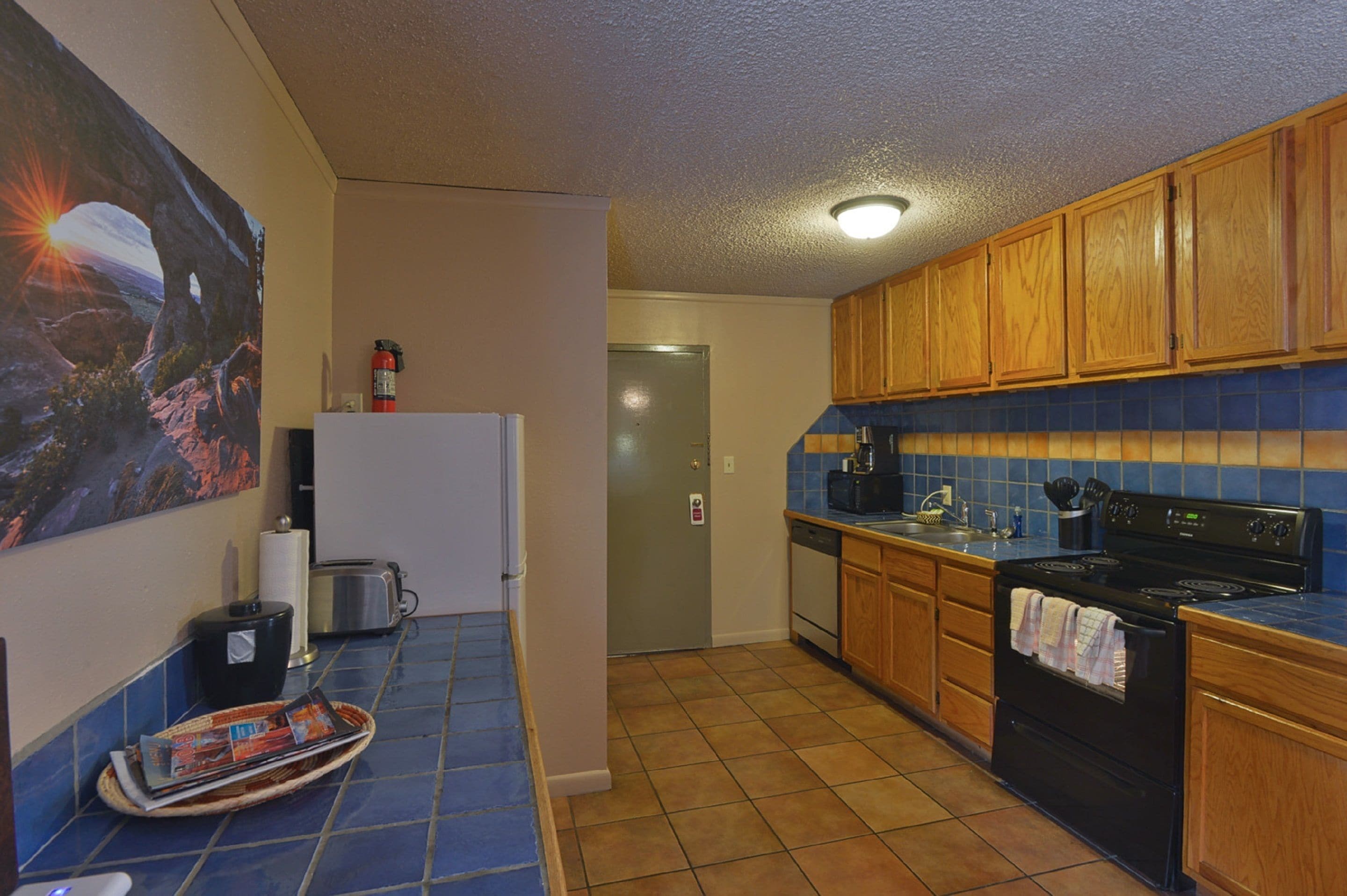 A kitchen with wooden cabinets, a black stove, and a blue tiled backsplash.