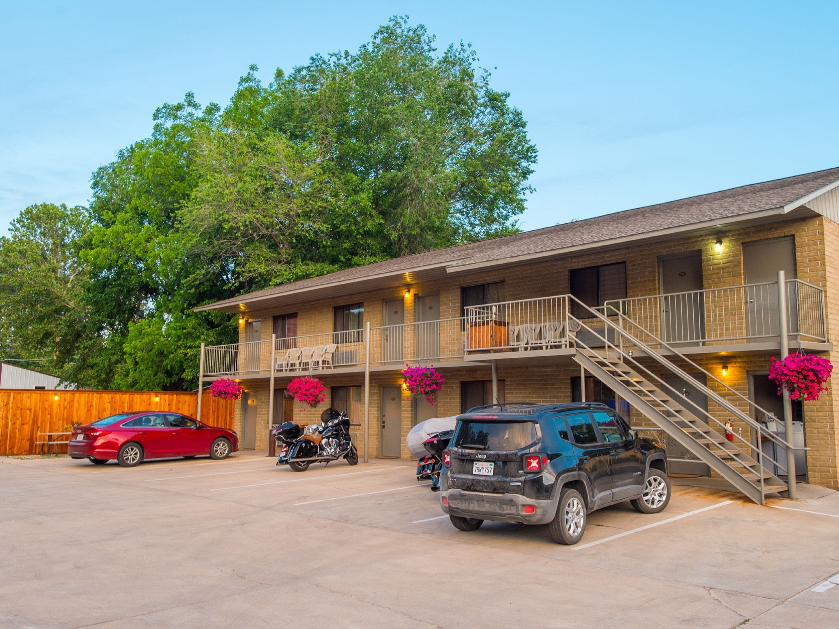 A motel with a two-story structure, outdoor parking, and a staircase leading to the upper level.