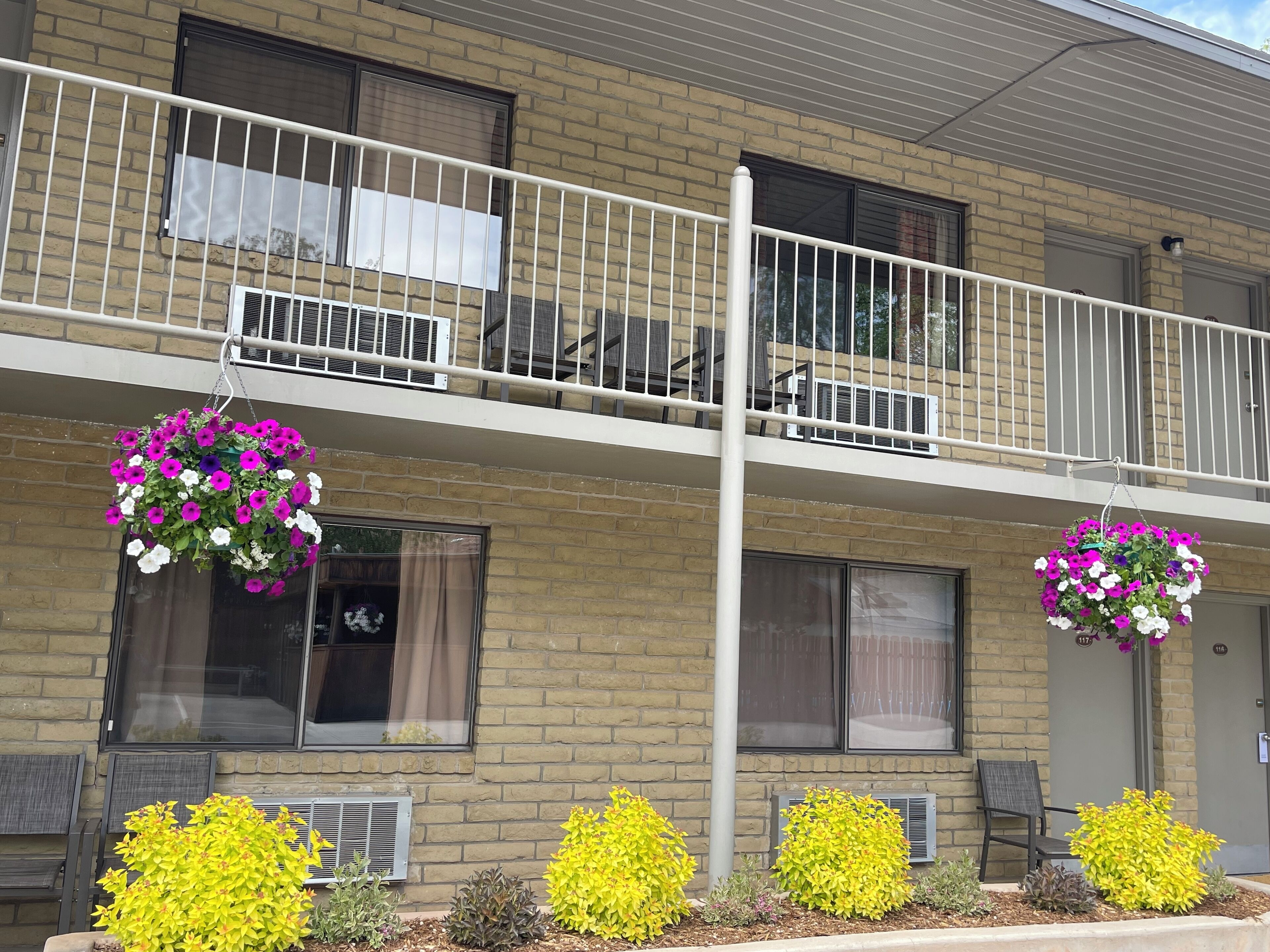 En toetagers bygning med balkon, aircondition og blomsterkasser.