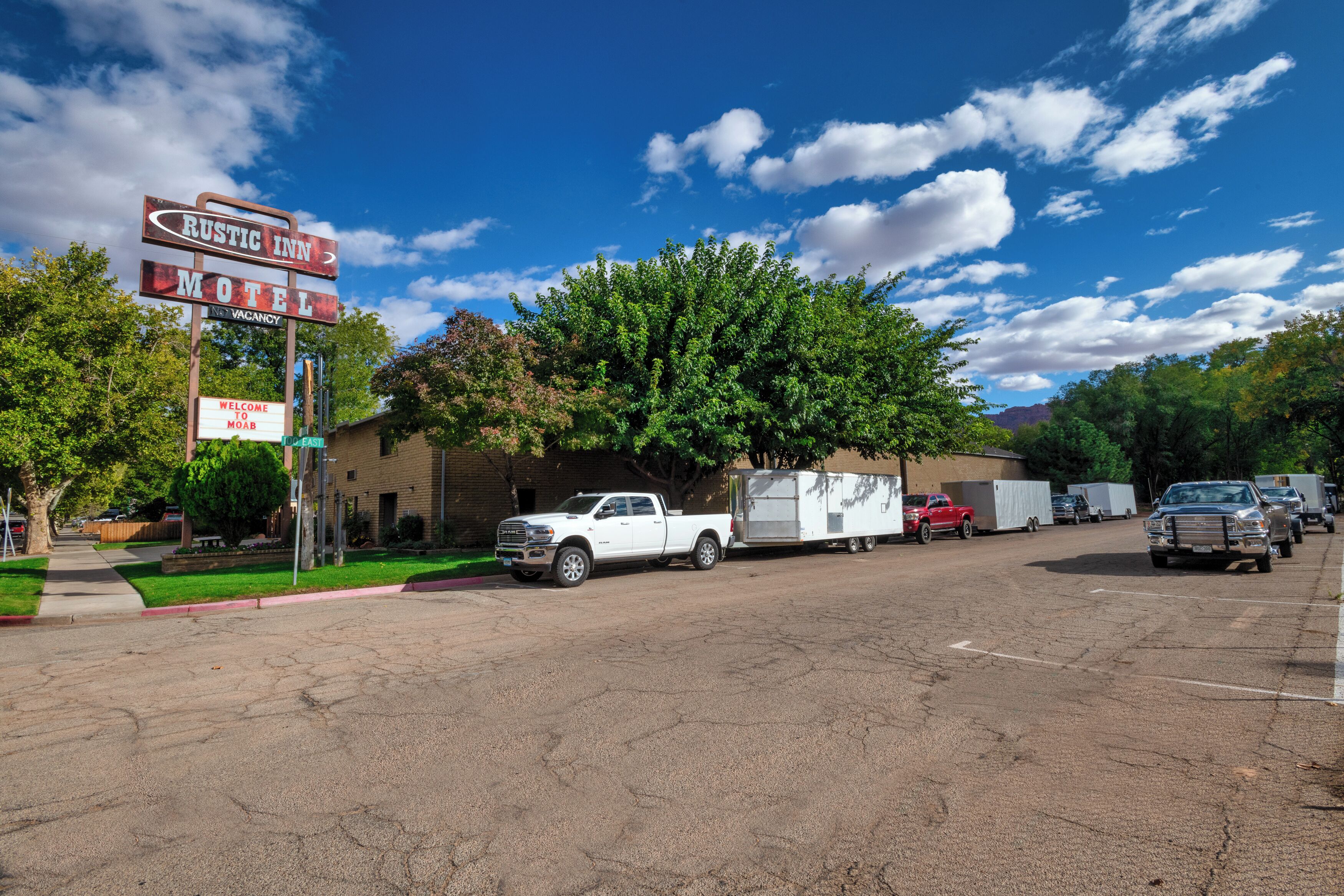 Un motel avec une enseigne, un camionnette blanche et une remorque.