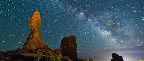 A starry night sky over a rocky landscape with prominent rock formations.