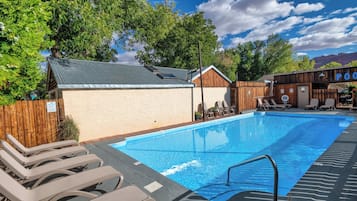 A swimming pool with lounge chairs and a wooden building with a sign that reads "POOD".