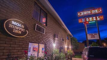 A brick building with a sign for 'Moab Rustic Inn' and a 'Rustic Inn Motel' sign indicating no vacancies.