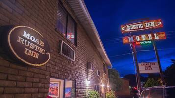 A motel with a rustic sign and a neon sign indicating it's the Rustic Inn.