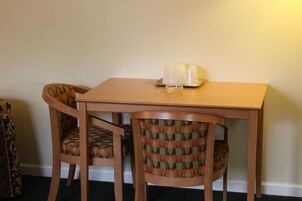 Una pequeña mesa de comedor con dos sillas, cada una con un cojín estampado. Hay dos vasos sobre la mesa.