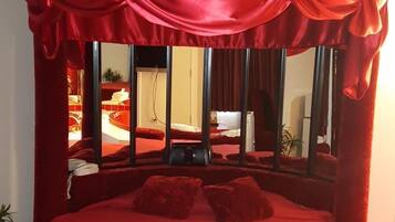 A large bed with a red canopy and a heart-shaped towel arrangement.