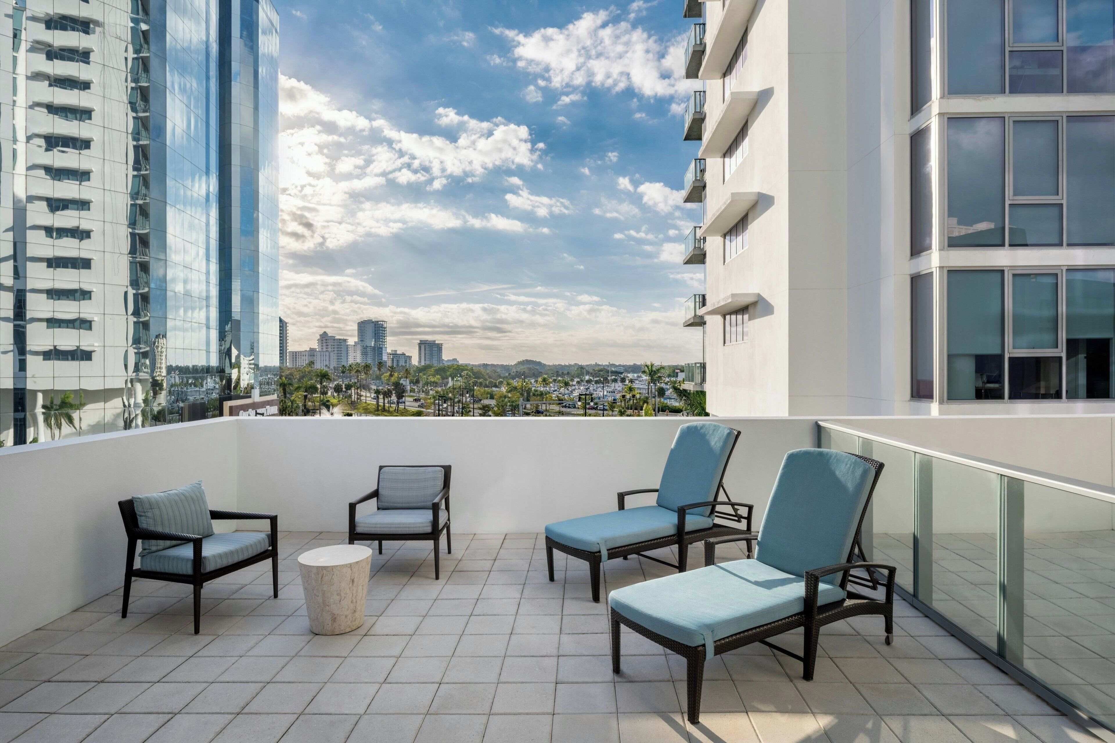 Une terrasse sur le toit, avec quatre chaises longues, une table ronde et une vue sur la ville.