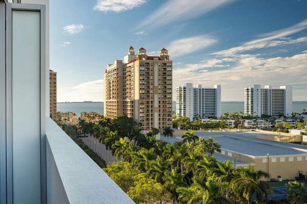 Un hotel moderno de gran altura con varias plantas, vista al mar y palmeras circundantes.