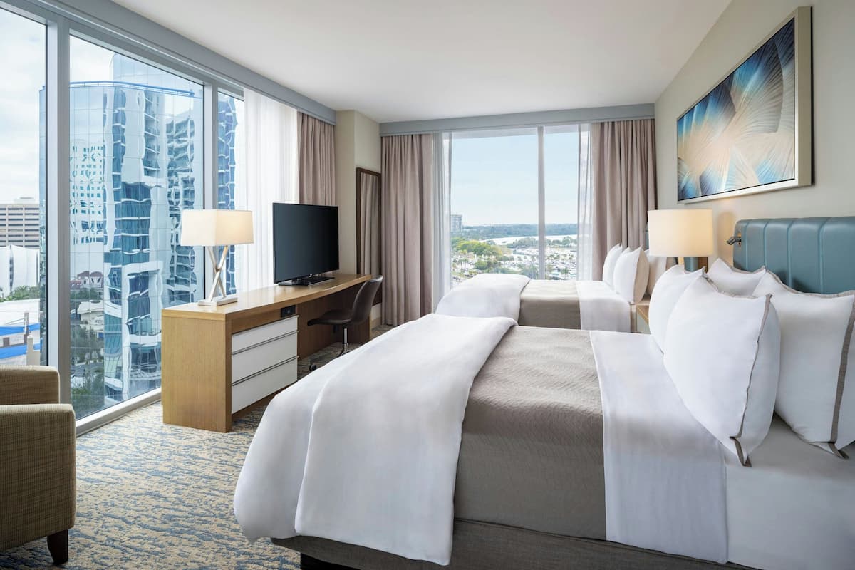 Ein Hotelzimmer mit einem großen Bett, einem Schreibtisch mit Fernseher und Blick auf die Stadt.
