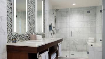 A modern bathroom with a marble shower, a large vanity with a mirror, and a built-in toilet.