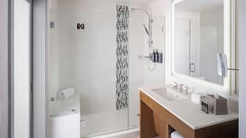 A modern bathroom with a glass-enclosed shower, a large mirror, and a wooden vanity.