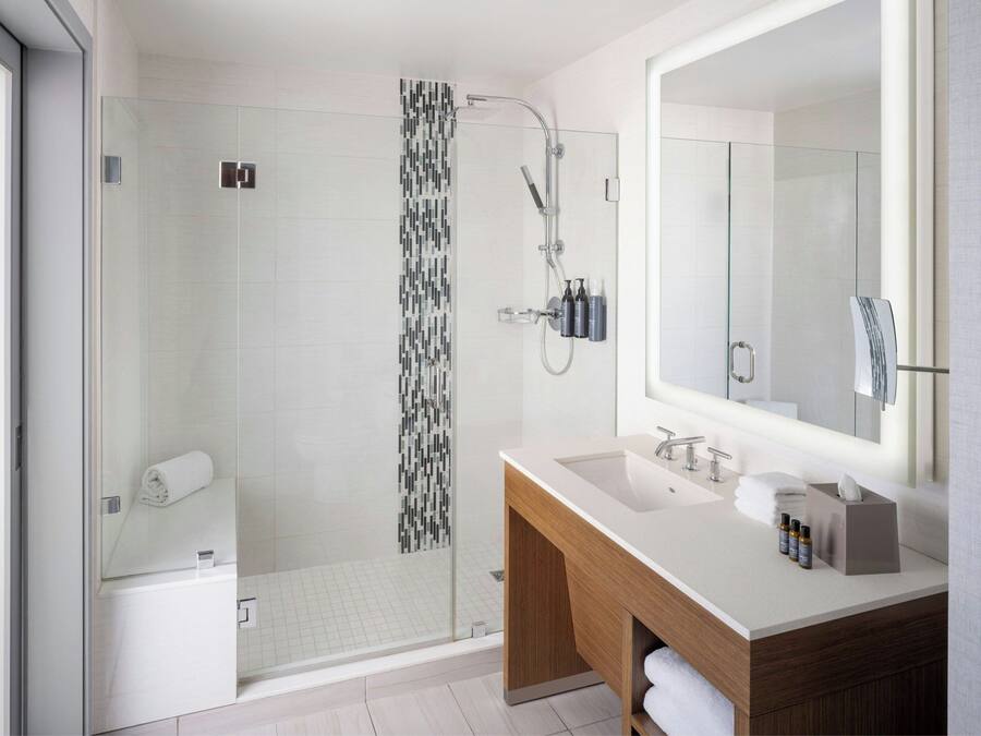 A modern bathroom with a glass-enclosed shower, a large mirror, and a wooden vanity.