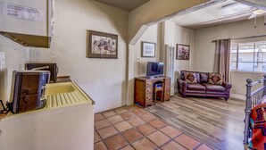 Una sala de estar con suelo de madera, un sofá, un televisor y un pequeño mueble de madera.