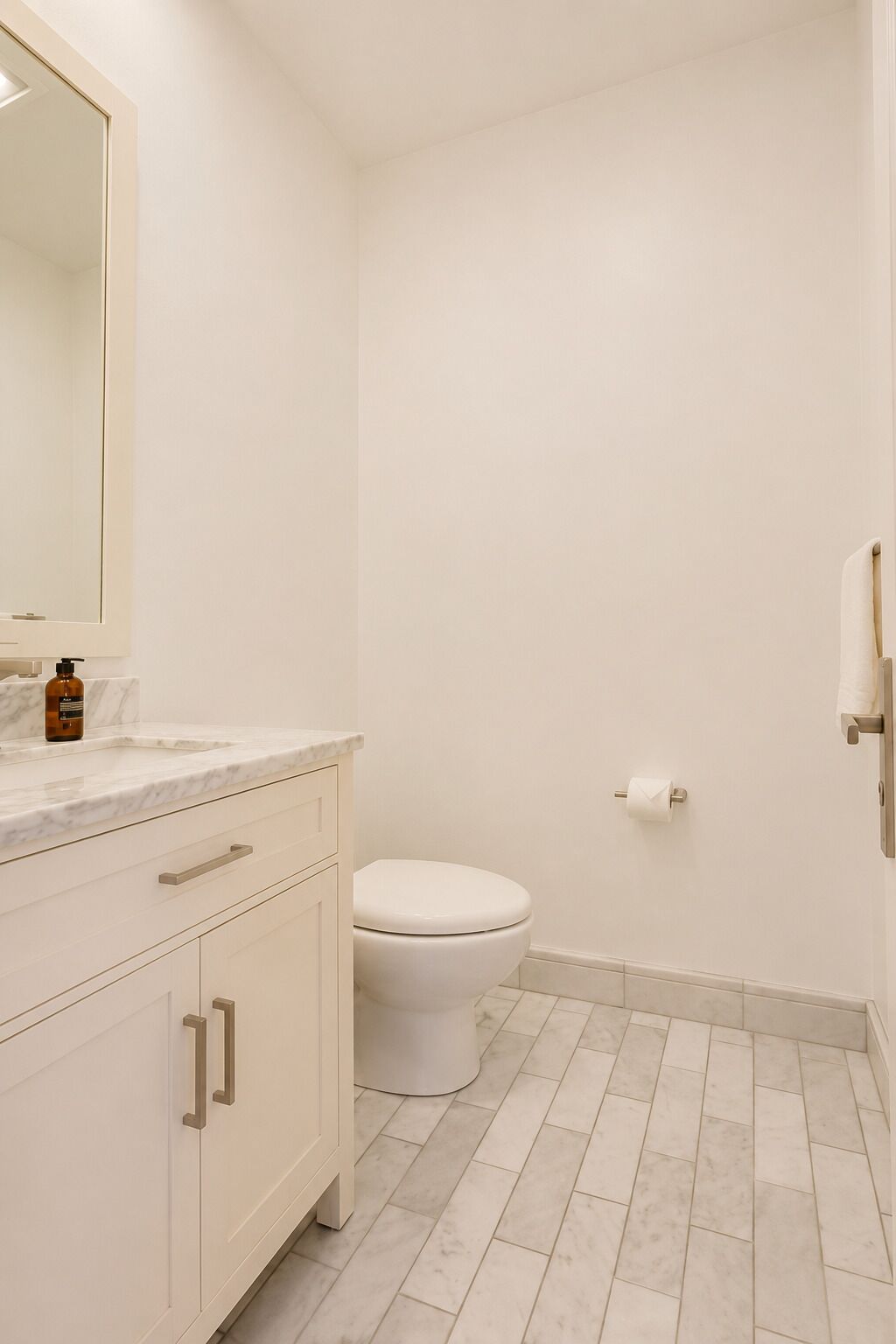 A bathroom with a toilet, a sink with a marble countertop, and a mirror.