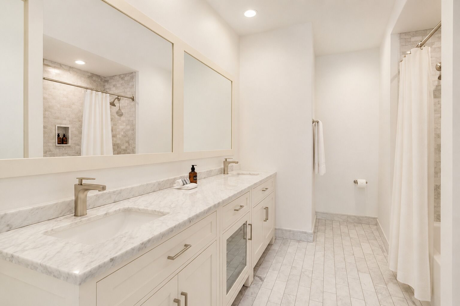 A bathroom with two sinks, a large mirror, and a shower area.