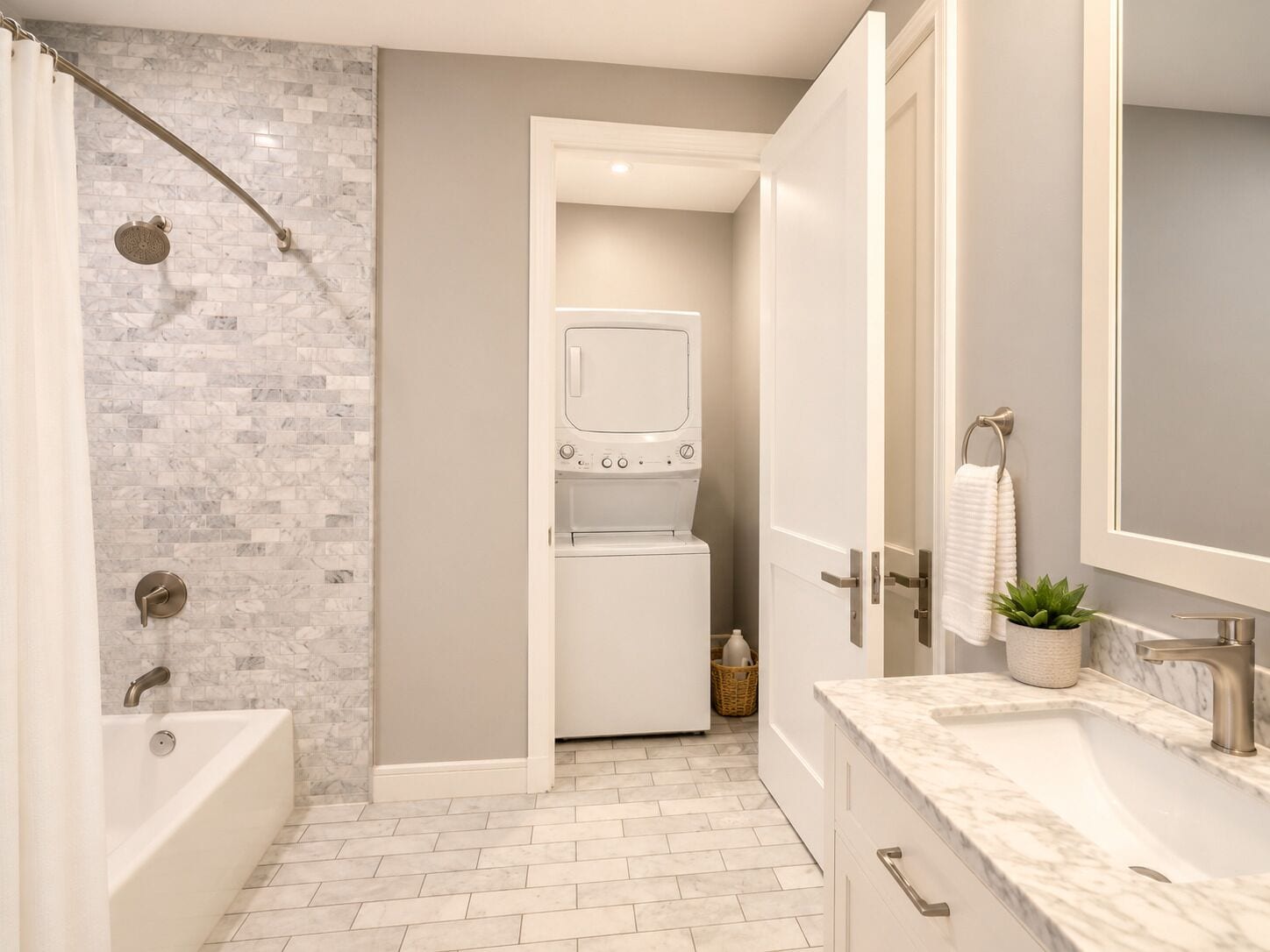 A modern bathroom with a shower, a built-in washing machine, and a large mirror.
