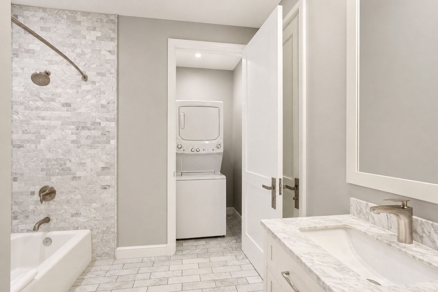 Un baño moderno con ducha, lavadora integrada y tocador con espejo.