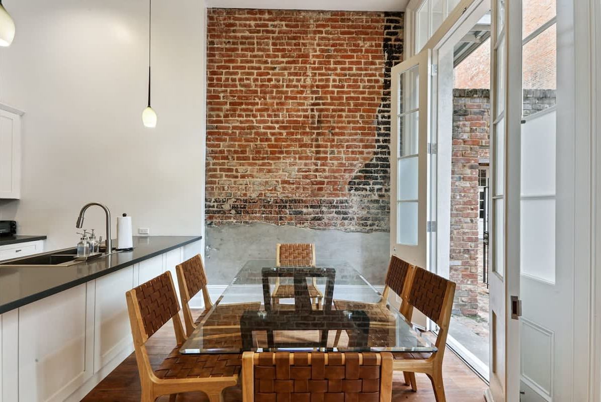 Una cocina moderna con pared de ladrillo, una mesa de comedor con sillas y vistas al exterior.