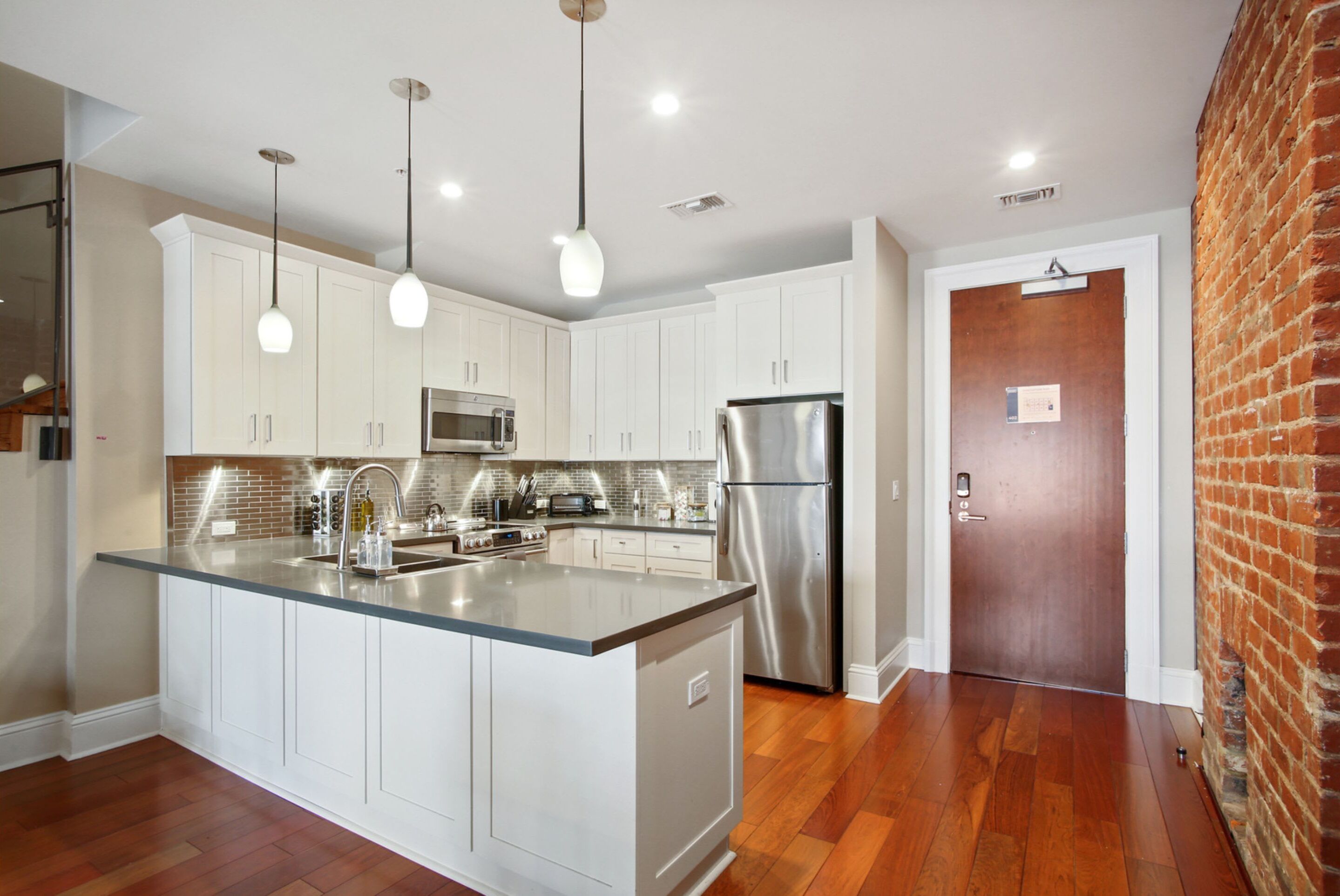 A modern kitchen with white cabinets, stainless steel appliances, and a central island.