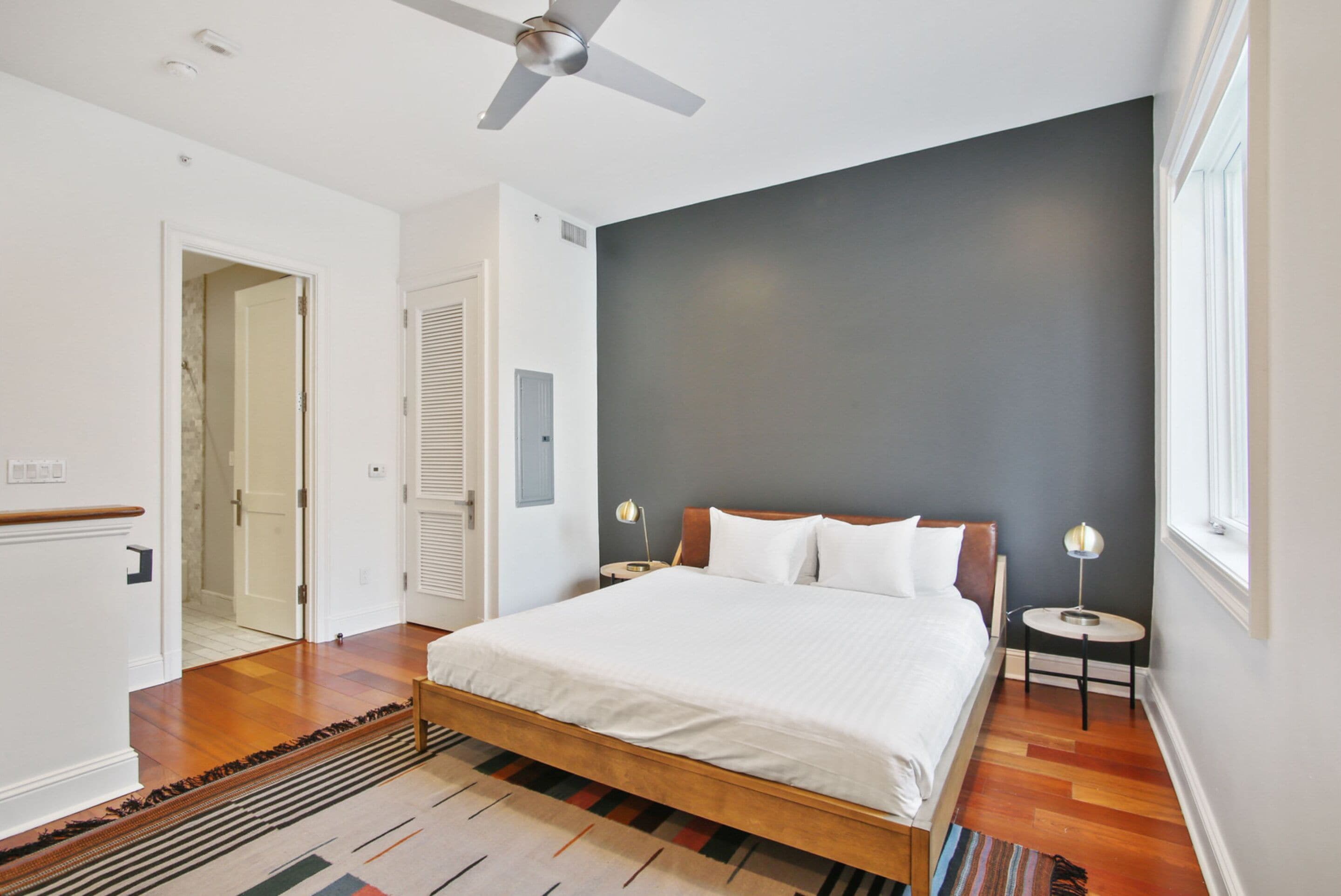 A bedroom with a bed, a ceiling fan, a nightstand, and a window.