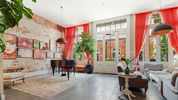 A spacious living room with a piano, comfortable seating, a large plant, and artwork on the walls. - Roami at Factors Row (New Orleans)