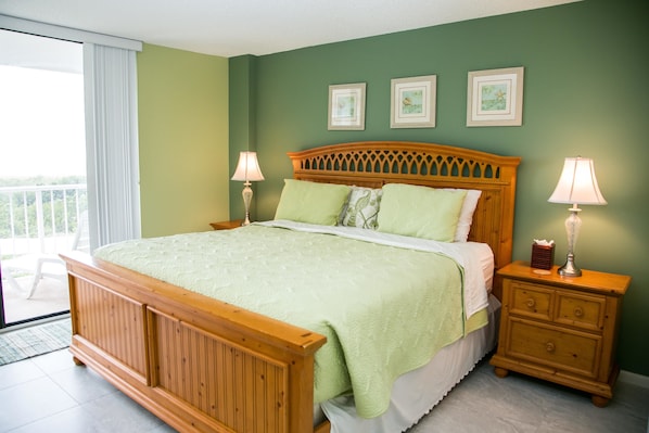 A bedroom with a wooden bed, green walls, and a balcony view.