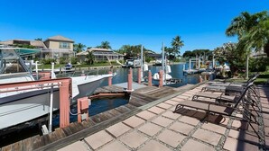 A marina with boats docked, a wooden dock, and lounge chairs. - 1650 Galleon Court (Marco Island)