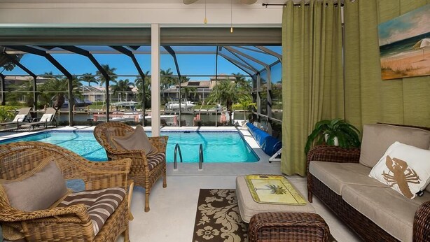 A poolside area with wicker furniture, a sofa, and a ceiling fan. - 1650 Galleon Court (Marco Island)
