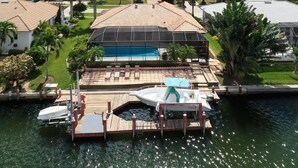 A residential property with a swimming pool, dock, and boats. - 1650 Galleon Court (Marco Island)