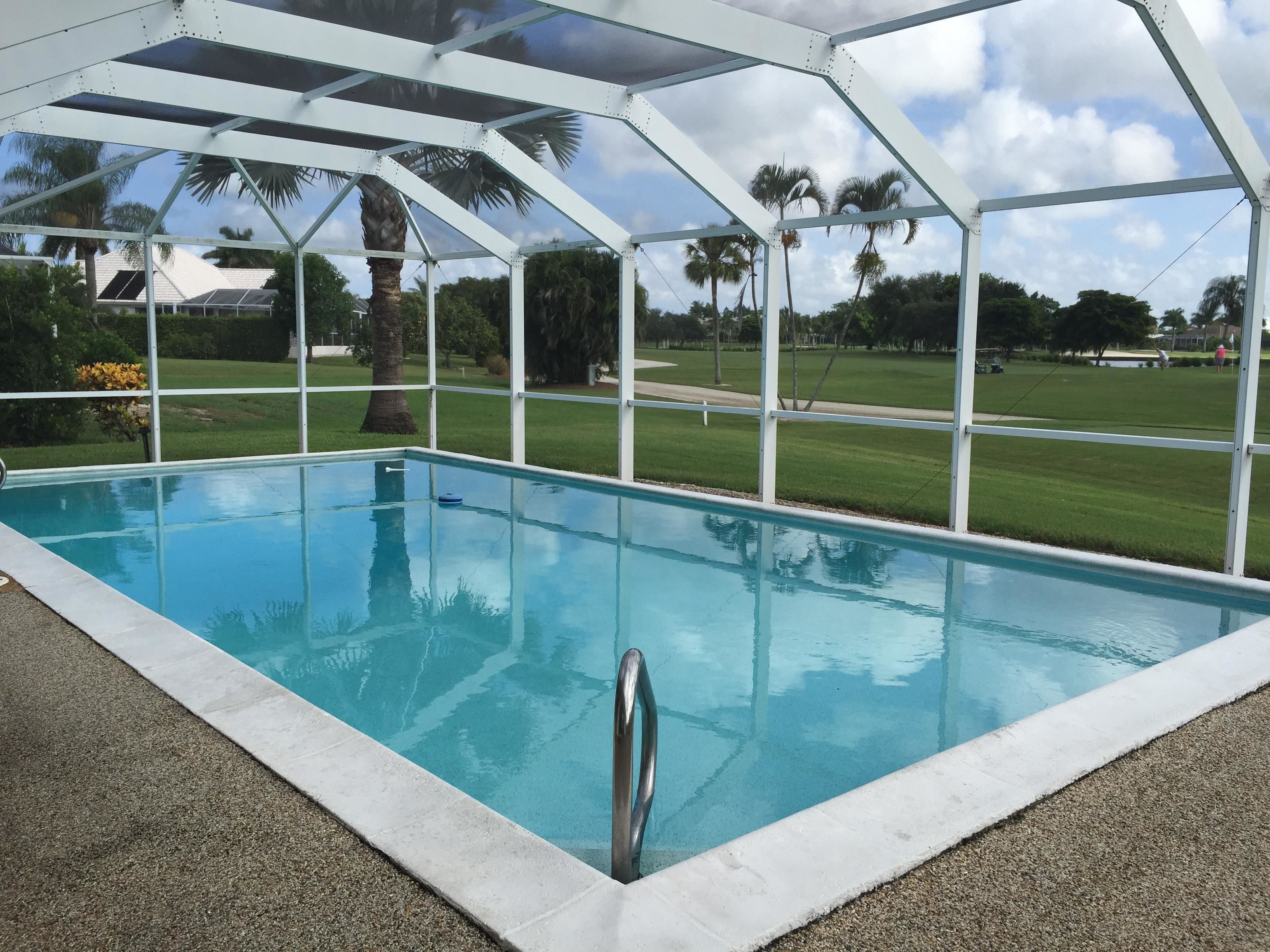 Une piscine aux eaux d’un bleu limpide, dotée d’un escalier en métal et entourée d’une structure en métal blanc.