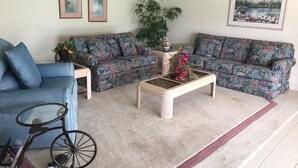 Ein Wohnzimmer mit zwei Sofas, einem Couchtisch, einem Fahrrad und gerahmten Bildern an der Wand.