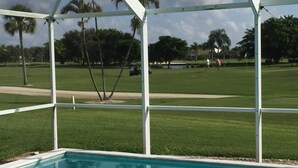 Ein Poolbereich mit Blick auf einen Golfplatz und Palmen.