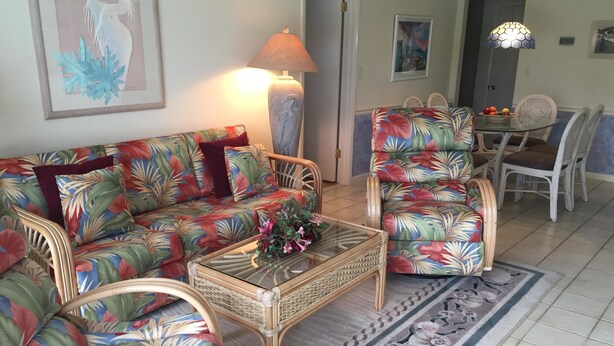 Ein Wohnzimmer mit einer Couch, Sesseln, einem Couchtisch und einem Essbereich mit Stühlen und Tisch.