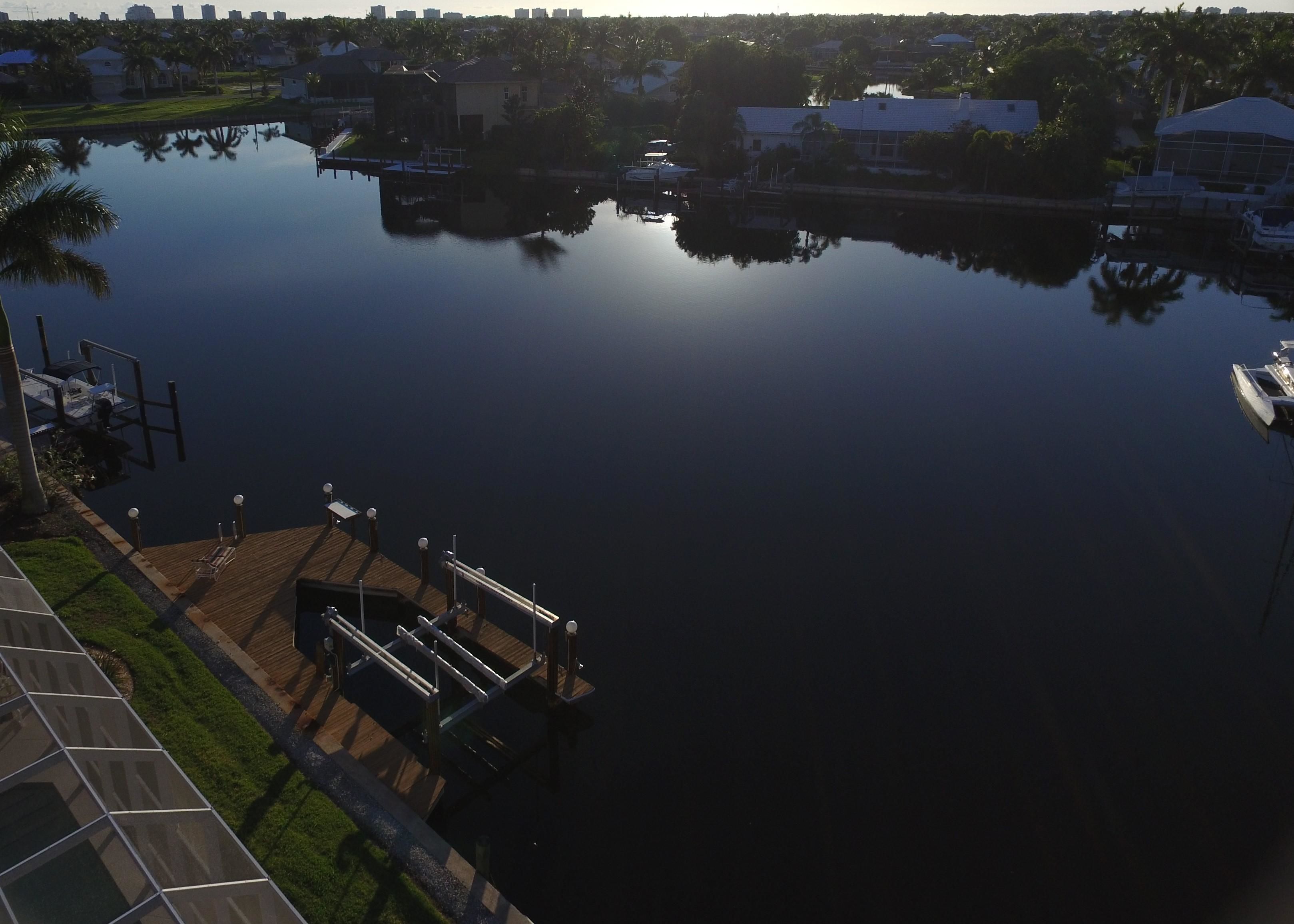 A calm water body with a dock and a bridge.