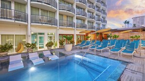 A hotel pool area with lounge chairs, a hot tub, and a view of the building's exterior. - The Laylow Waikiki, Autograph Collection (Honolulu)